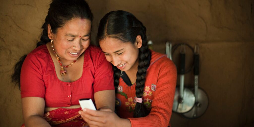 happy daughter showing mobile phone to her mother in a blog about send money to Nepal from Australia